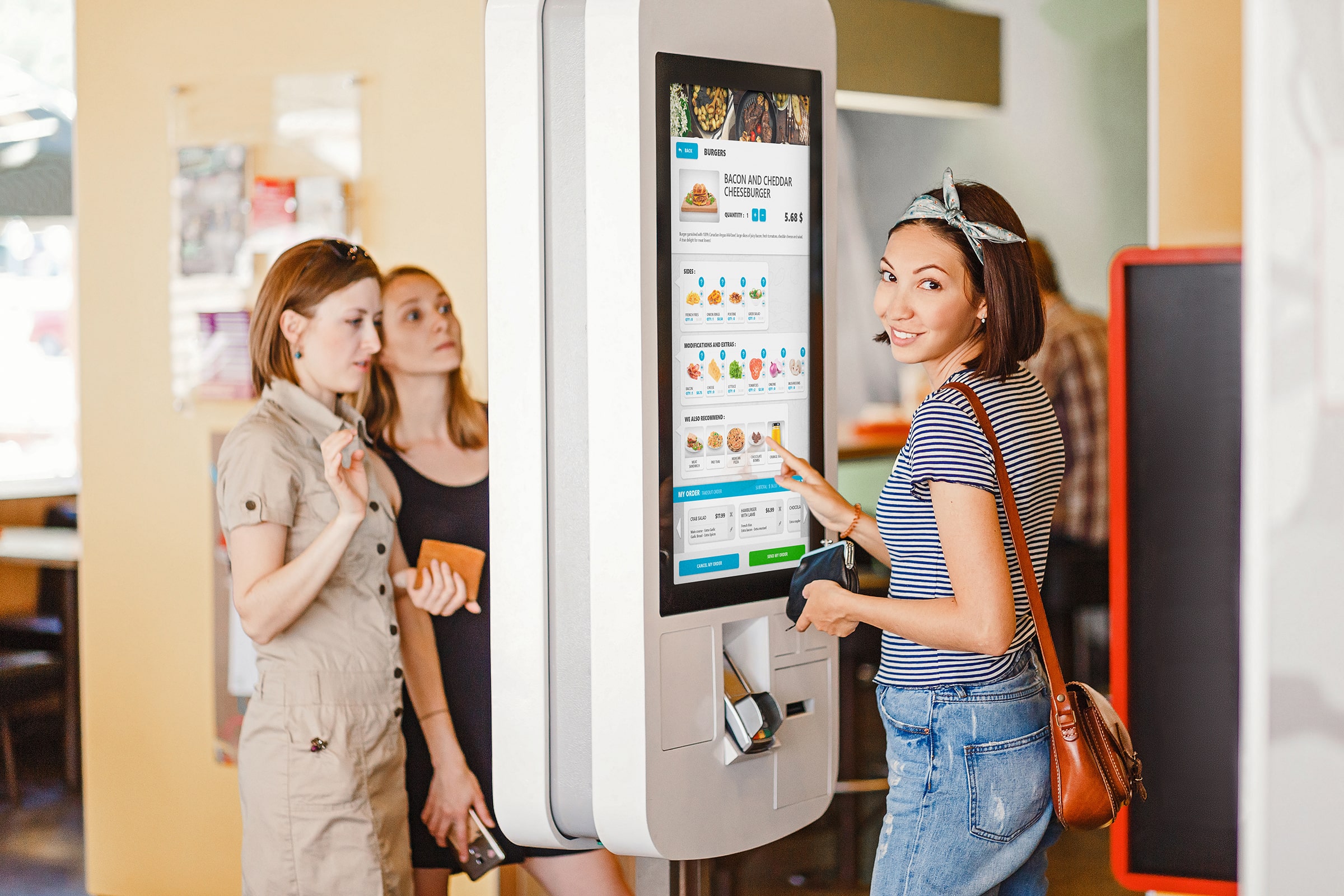 A customer interacts with a Veloce self-service kiosk, demonstrating the system's user-friendly interface for placing orders in a quick-service restaurant.